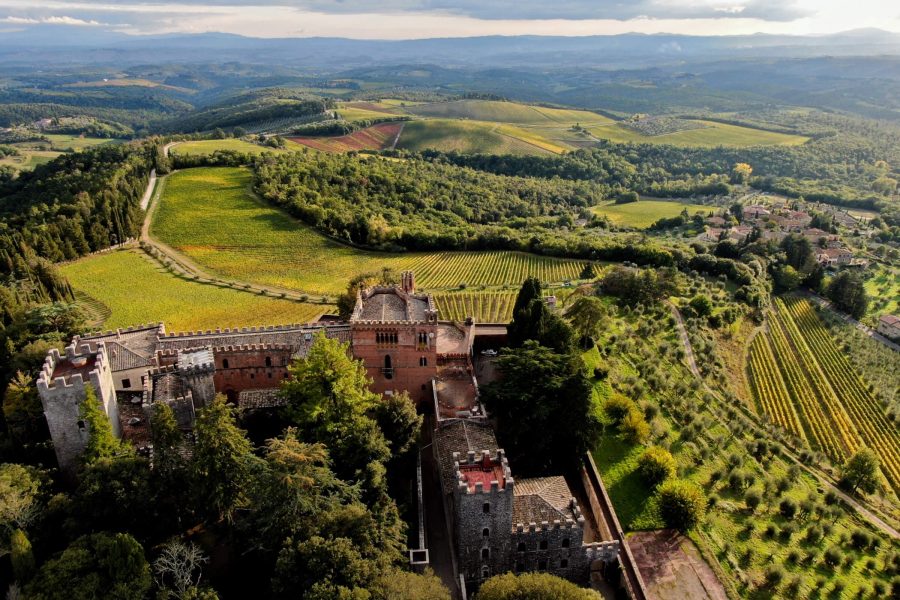 Aerial view of the Barone Ricasoli winery in Italy, featuring a historic castle nestled among lush vineyards and rolling hills.